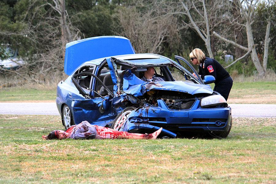 At the mock car crash, a police officer looks in on Colton Wells, the drunk driver. Outside the car, Aubree Zuniga was one of the crash victims. The scene was part of Shine On, a version of the Shattered Dreams program.