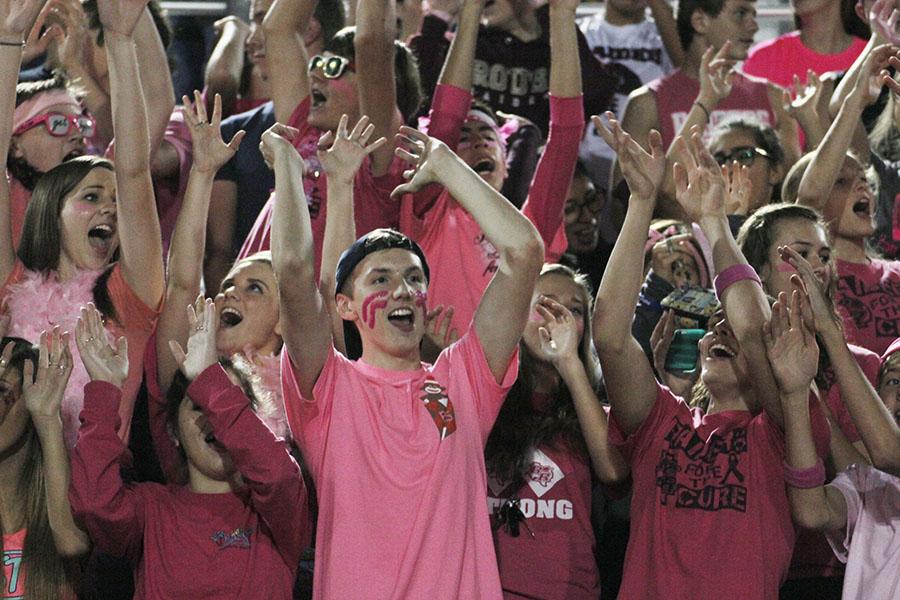Junior Sam Paulsen (center) cheers while the drumline plays at the Pink Out game against McNeil