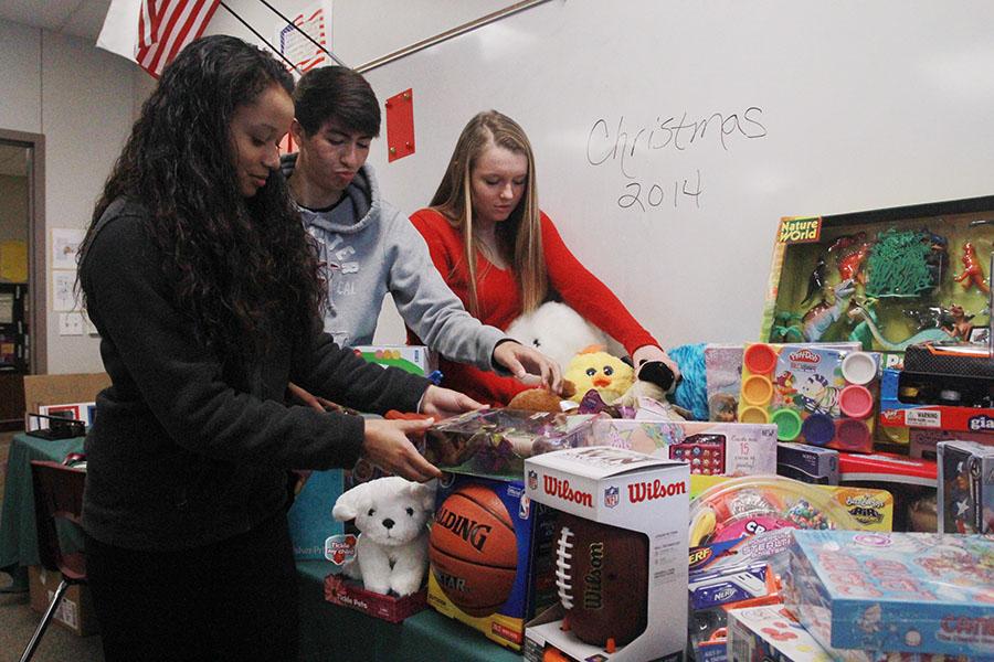 Students Raza Mahmoud, Justin Oviedo and Cassidy Morgan work together to give presents to children that otherwise wouldnt have any