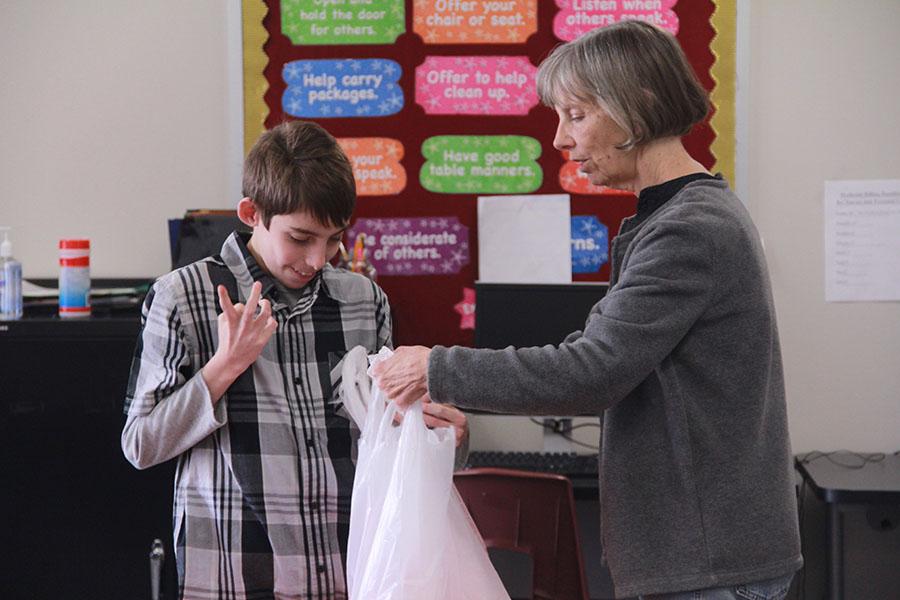 Freshman Layne Moffett helps teacher Cathy McDaniel fill a bag for LISDs Backpack food program.