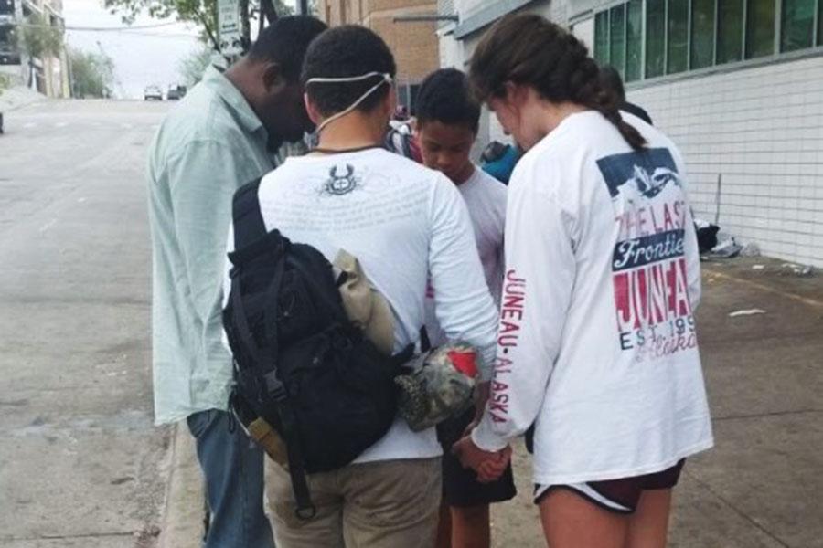 Sophomore Lila Lilljedahl (right in white shirt) prays with members of her youth group in downtown Austin. Lilljedahl participated in a local mission trip to help feed the homeless during spring break.