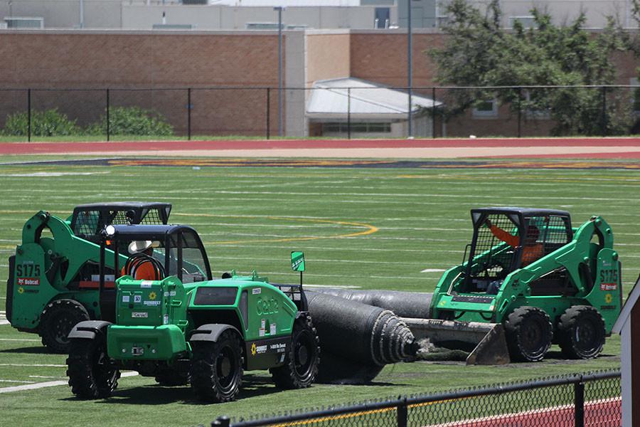 Construction workers roll out the new turf on the field.