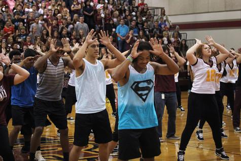 Varsity football players join in on the dance on the gym floor.