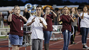 ASL III students, include Nicole Laird (right) sign at the Cedar Ridge football game.