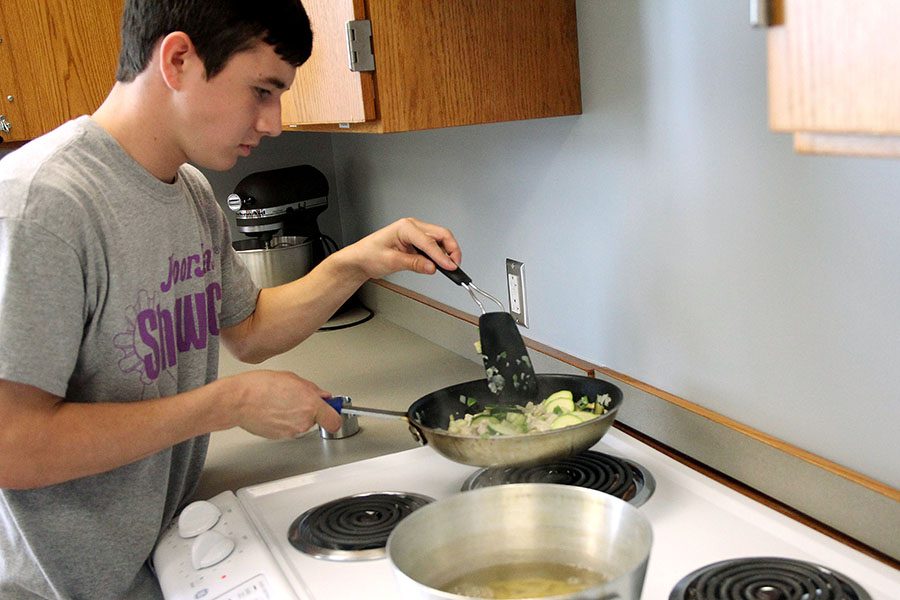 Caleb Wilson stirs vegetables on the stovetop.