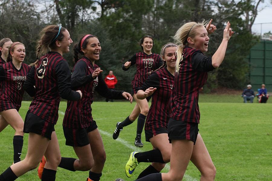 Abby Schrader (right) and the varsity soccer girls celebrate a goal in the New Braunfels match. The goal helped the team tie the Unicorns 1-1 in the tournament.