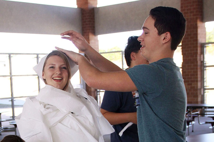 Justin Rudi (right) wraps Paige Wilson in toilet paper for a mummy contest at the October  Amazing Raiders Club meeting.
