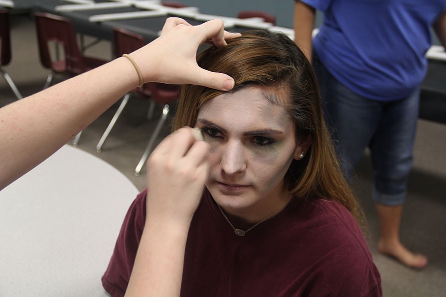 Senior Reagan Hjort sits while make-up is added. All of the students chosen as the living dead were painted with gray make-up and not allowed to speak or use their phones.