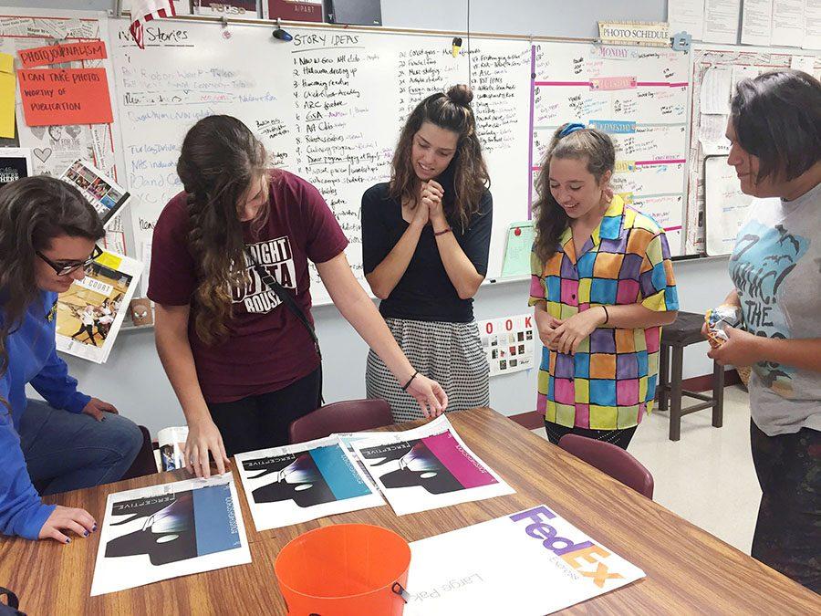 COVER ME Senior Kelsey Staber, juniors Grace McNamara and Keesley Strohschein, sophomore Chloe Hatfield and junior Jaci Chavera look at proofs of the yearbook cover. The staff chose to have Plexiglas combined with three different colored covers. “I think it’s really cool that we’re making the book different this year,” Chavera said. “The Plexiglas along with the three colors really suits the theme well.” 