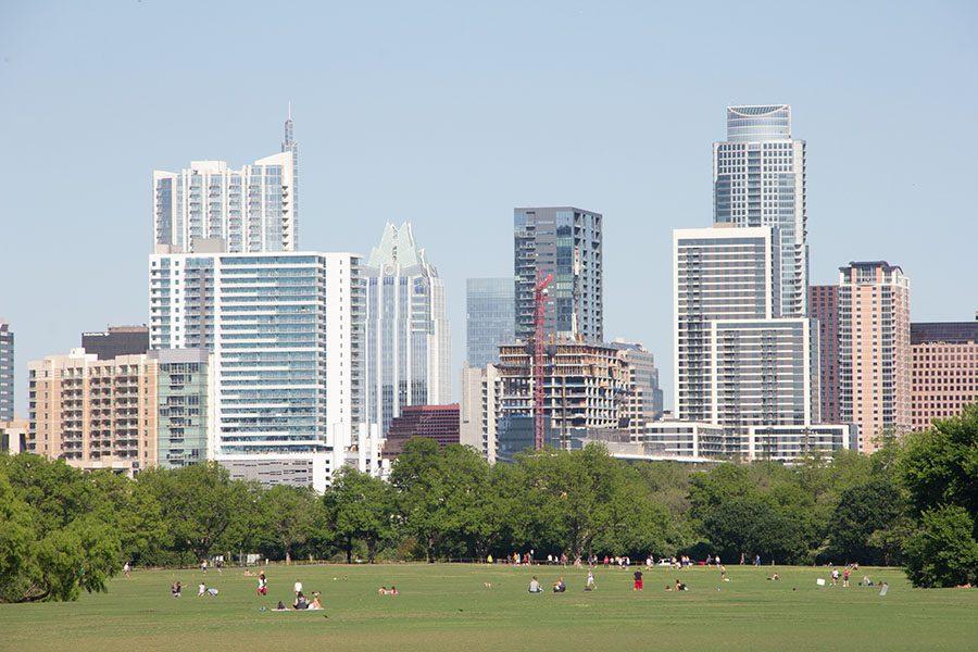 The Austin skyline sits in the background of people spending time near Lady Bird Lake. Zilker Park, Auditorium Shores and the hike and bike trail all are great places to enjoy the outdoors and take in the Austin scenery.