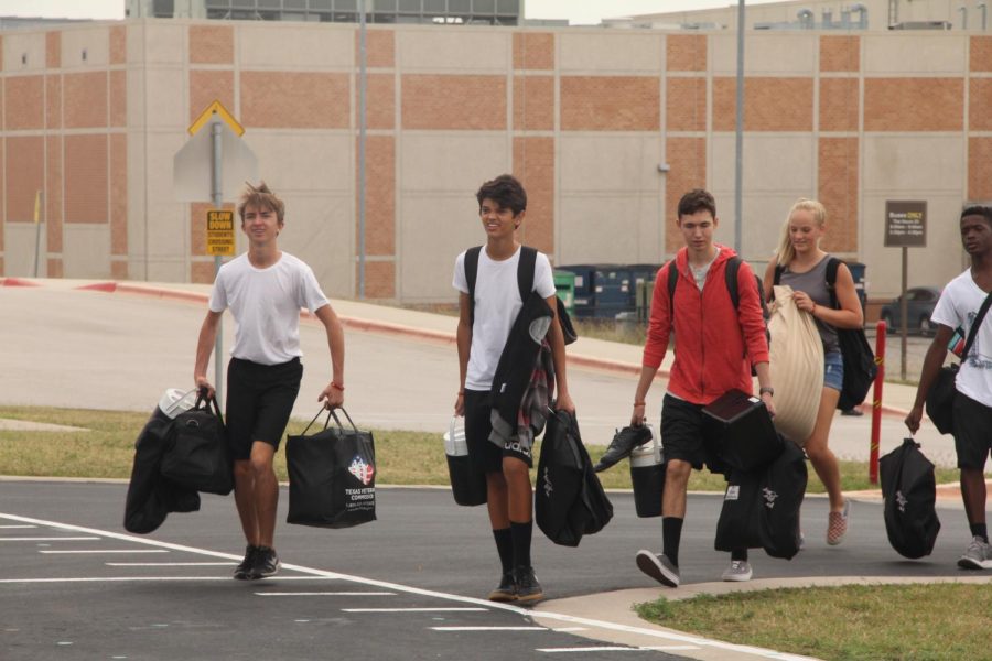 Students carry uniforms to load the buses for State.
