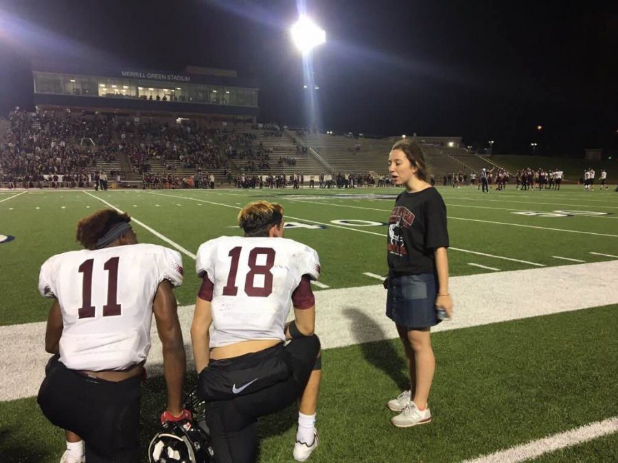 Head football manager Chloe Hatfield talks to several players before a game.