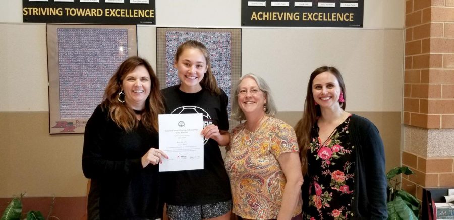 Principal Christine Simpson presents senior Emily Forster with her NHS scholarship, while sponsors Marguerite Swilling and Megan Pilewski show their support.
