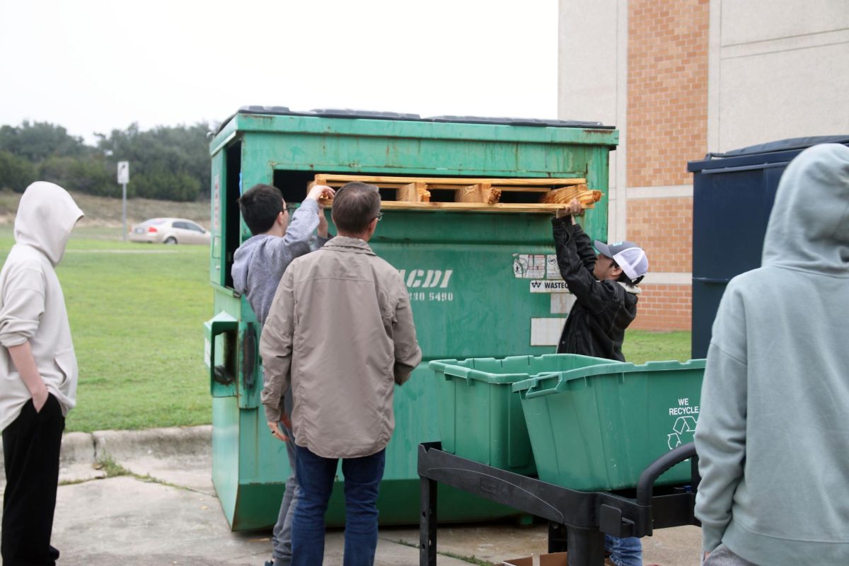VA Students push a wood pallet into the recycling bin outside of school on Nov. 13.