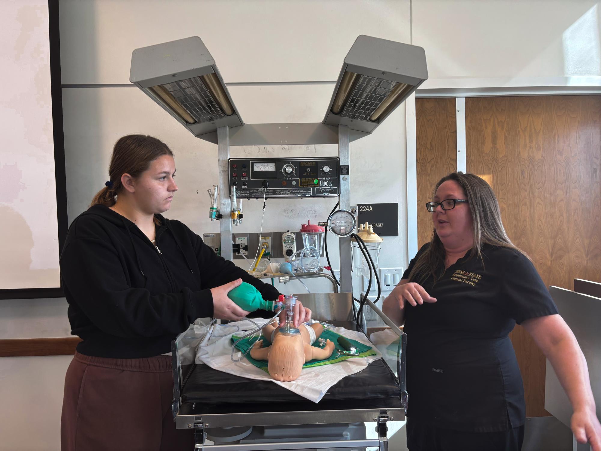 Senior Kayla Hehenberger learns how to use an infant manual resuscitator during a simulation with a professor from the Texas State Department of Respiratory Care.
