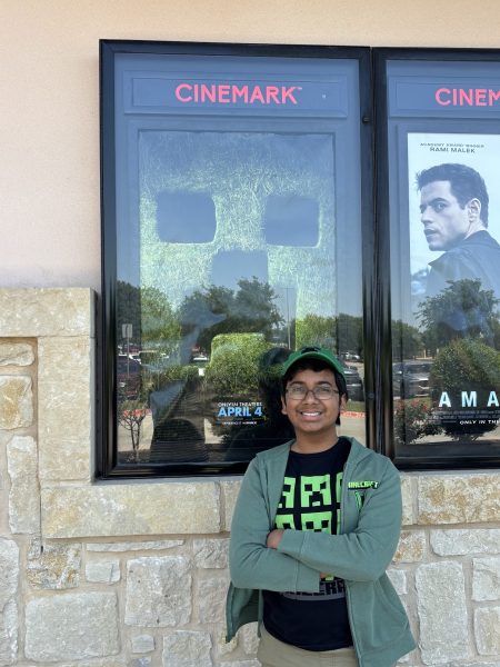 Freshman Sandeep Shenoy poses in front of a promotional poster for “A Minecraft Movie,” wearing Minecraft-themed merchandise. “I remember fondly the first time I played Minecraft, along with the many memories that followed,” Shenoy said. “I’m glad to see the next generation of kids pick up Minecraft, especially after watching the new movie.”